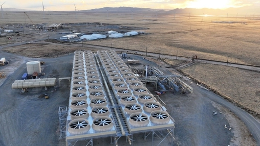 Overhead shot of a geothermal energy facility with dozens of fan units arranged in rows across a desert site