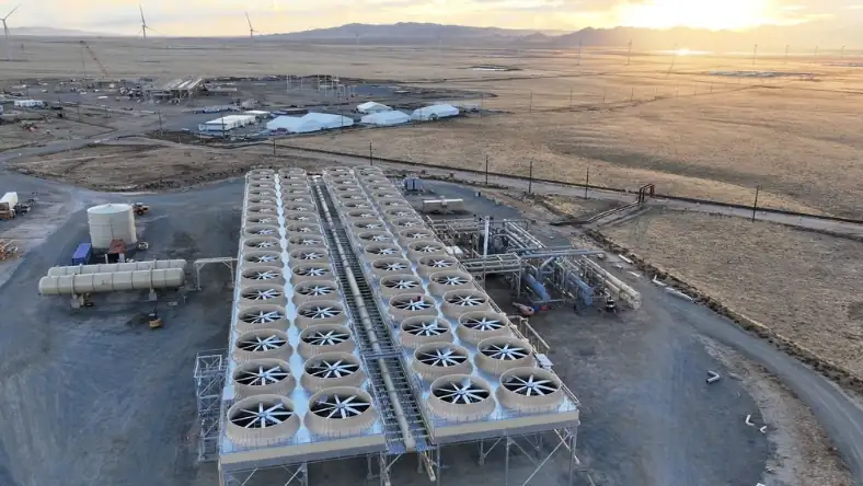 Overhead shot of a geothermal energy facility with dozens of fan units arranged in rows across a desert site