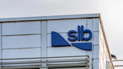 SLB branded building with a blue geometric logo and lettering on a white industrial facade under grey sky