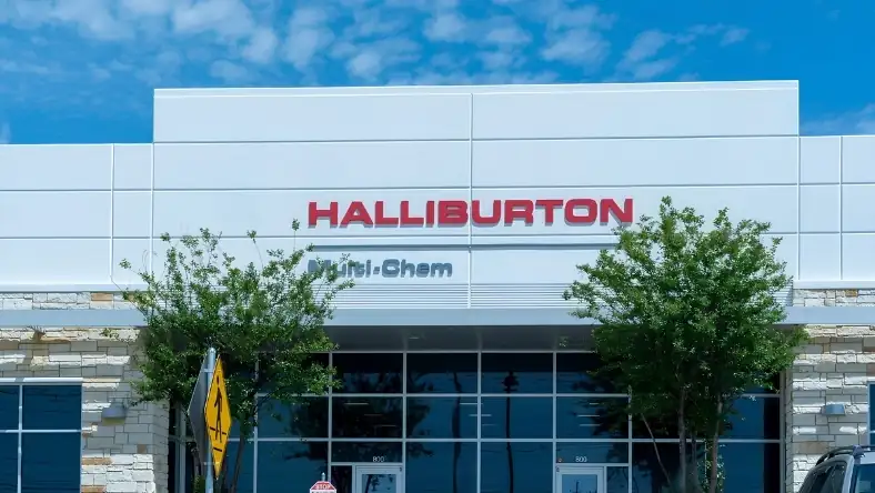 A commercial building exterior with large red Halliburton signage and a Multi-Chem sign below under a blue sky